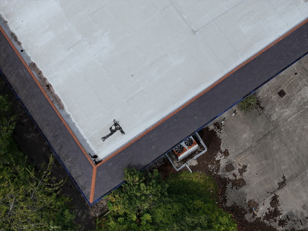 Drone inspection of a flat roof commercial building in Leeds, West Yorkshire, assessing roofing materials and potential maintenance issues.